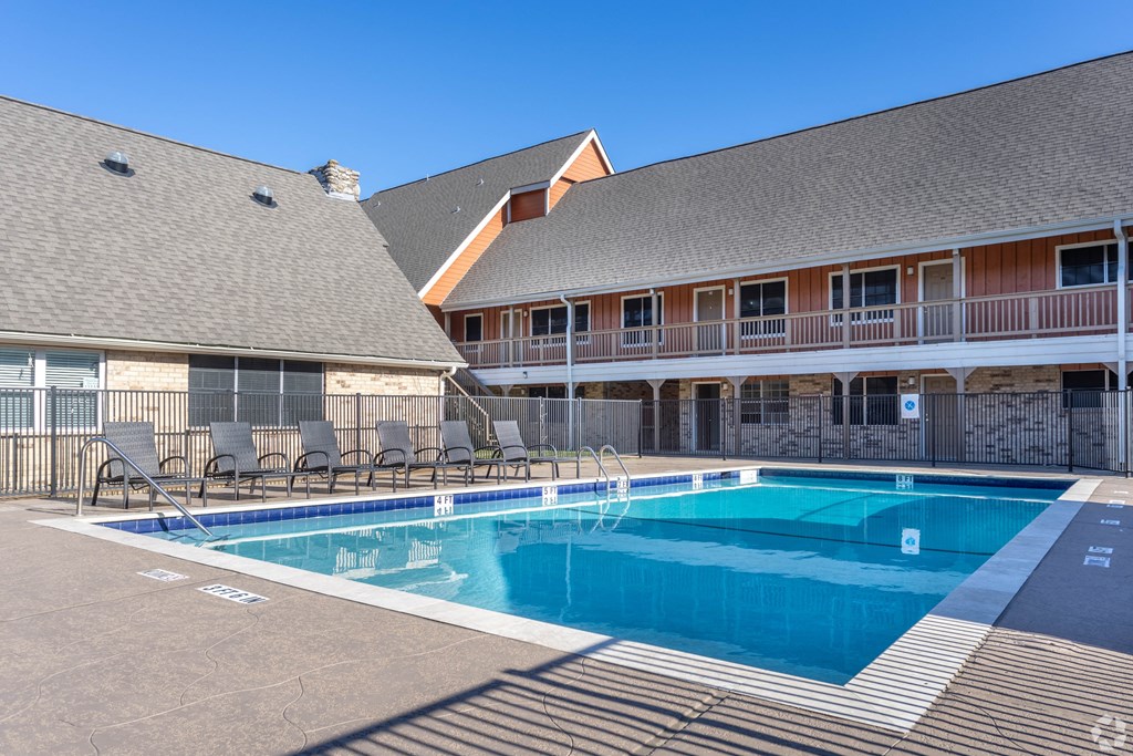 a swimming pool with chairs in front of a building