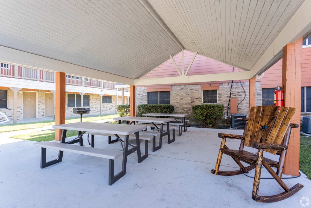 a covered patio with tables and chairs in front of a building