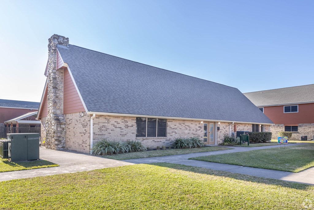the front of a brick house with a lawn and a driveway