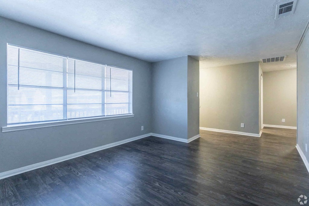an empty living room with wood floors and a large window