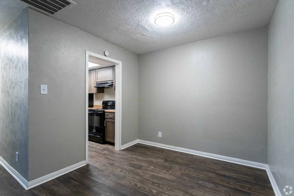 a room with a door to a kitchen and a hard wood floor