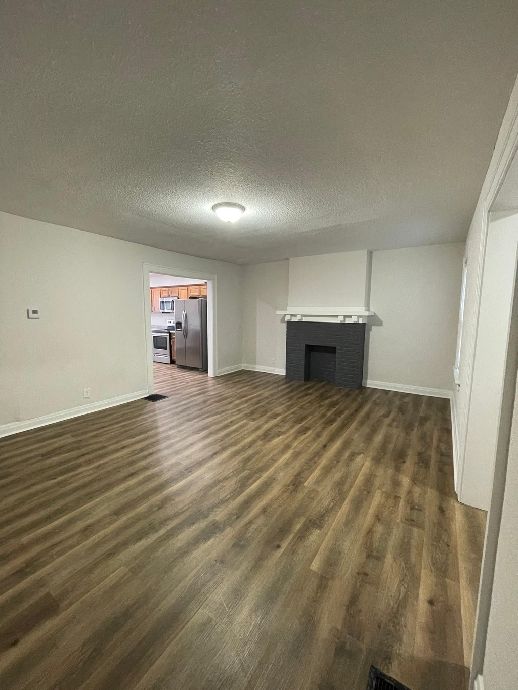 an empty living room with wooden floors and a fireplace