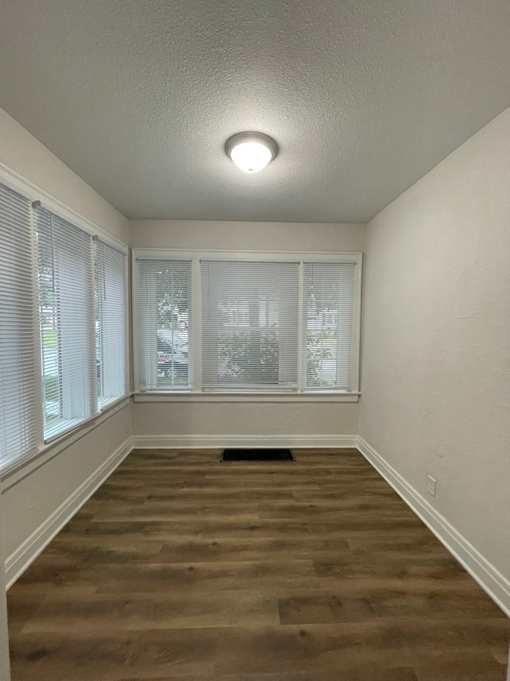 the spacious living room of an empty home with a large window