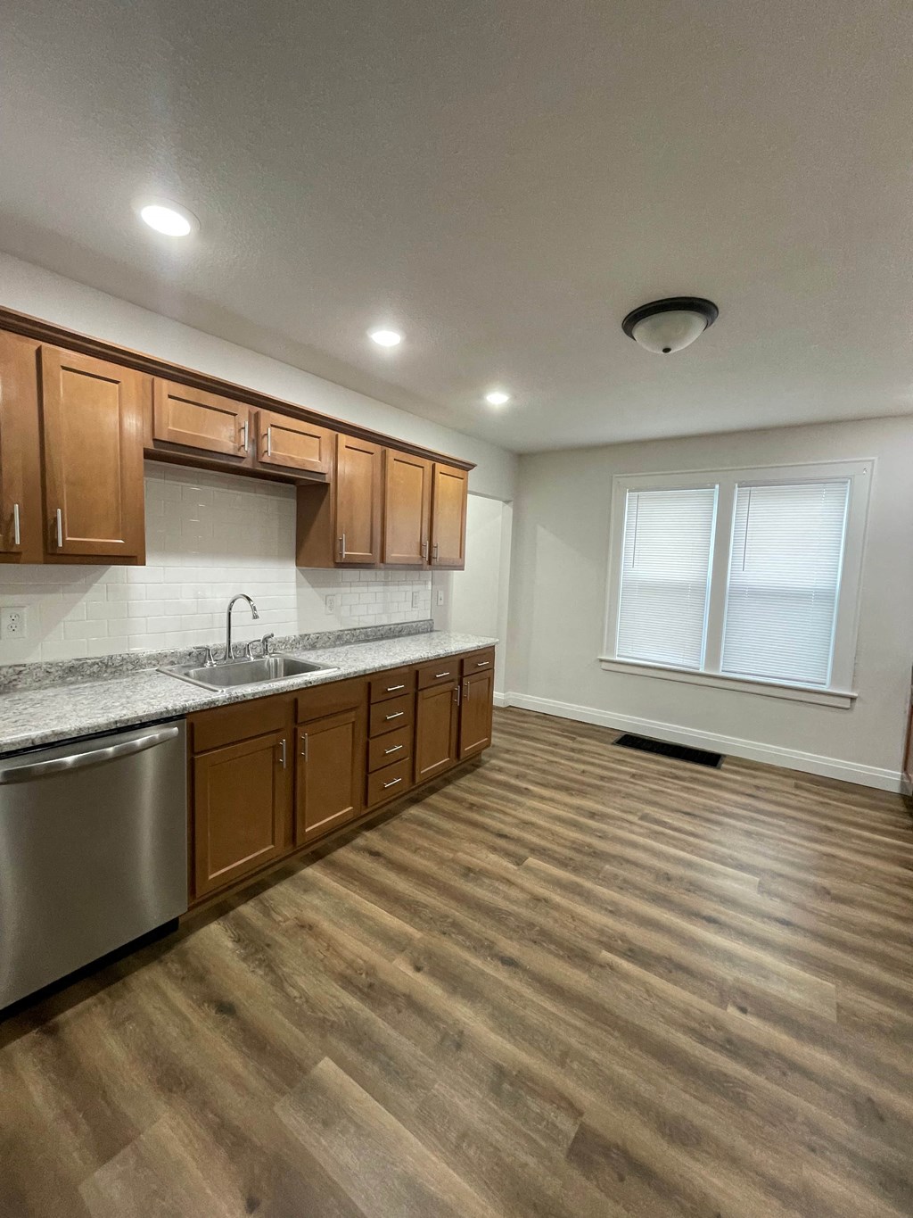 an empty kitchen with wooden flooring and stainless steel appliances