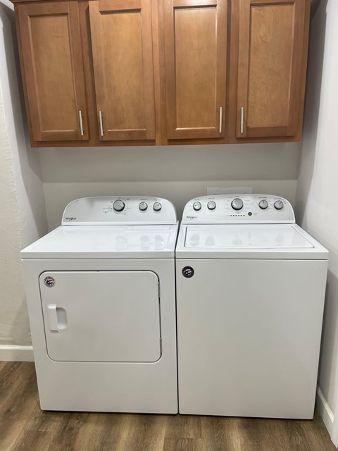 A pair of white front loading washing machines in a laundry room.