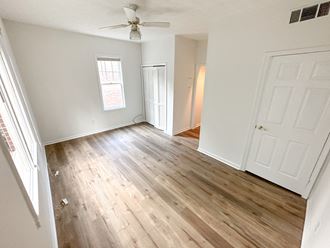 an empty living room with hardwood floors and a ceiling fan
