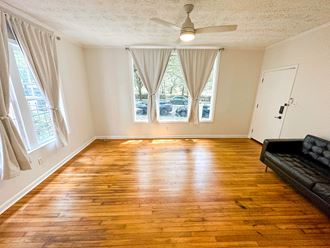 an empty living room with a hard wood floor and a black couch