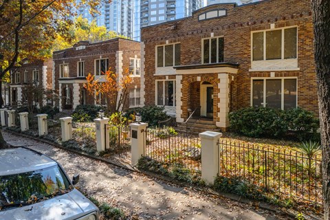 a small brick house with a fence and a car parked in front of it