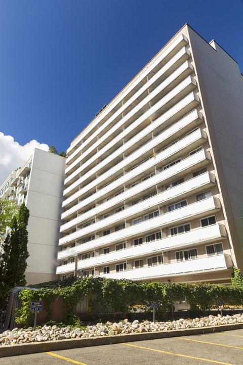 A tall white building with balconies on the upper floors.