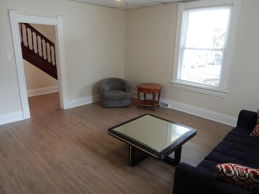 A living room with a black couch and a glass coffee table.