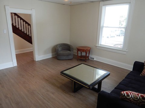 A living room with a black couch and a glass coffee table.