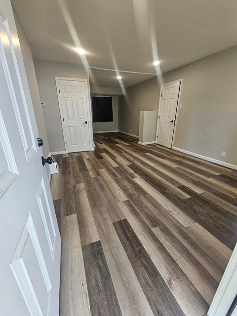 A room with white doors and wood flooring.