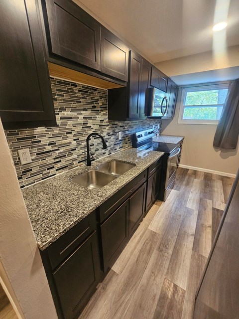 A kitchen with black cabinets and a granite countertop.