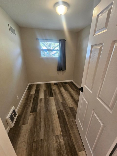 A room with a wooden floor and a white door.