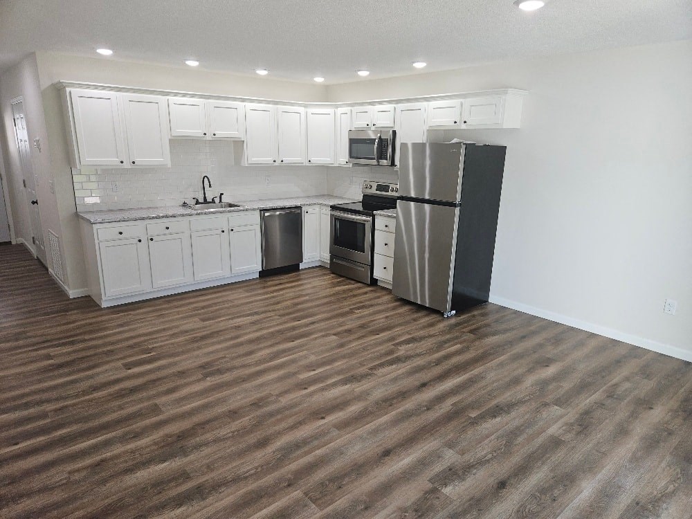 a kitchen with white cabinets and a stainless steel refrigerator