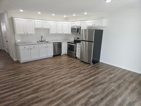a kitchen with white cabinets and a stainless steel refrigerator