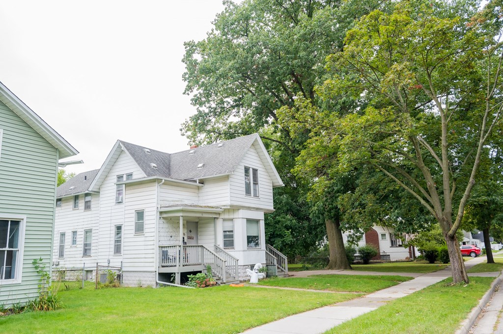 a white house on the side of a street with trees