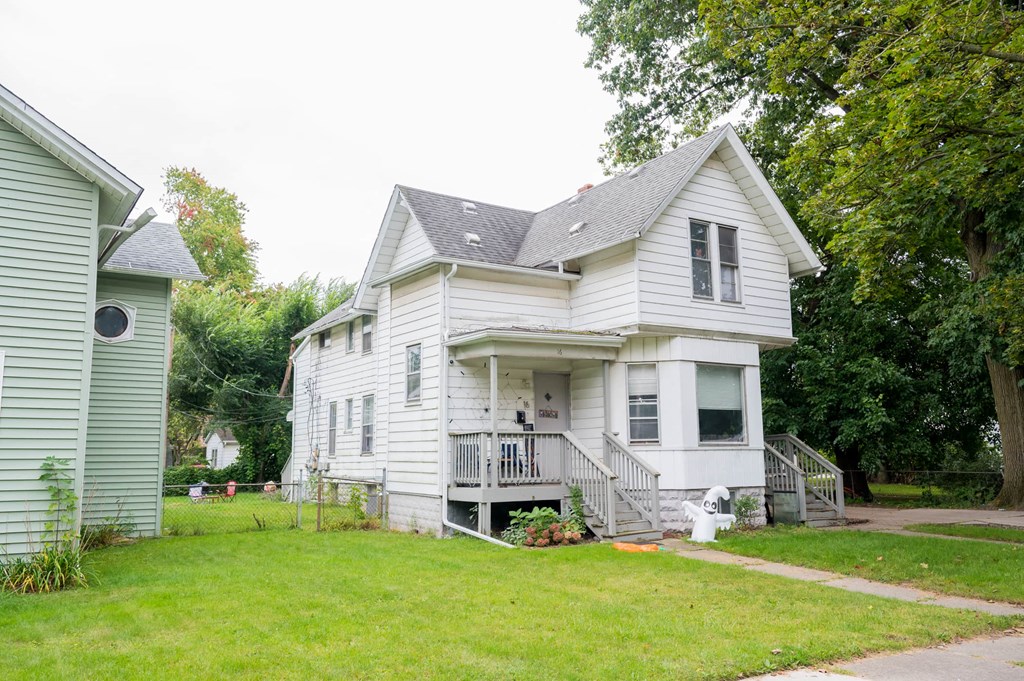 a white house with a porch and a green yard