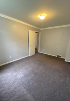 an empty living room with a carpeted floor and white walls