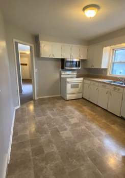 an empty kitchen with white cabinets and a sink