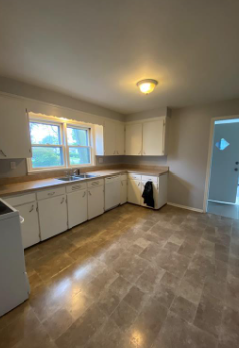 an empty kitchen with white cabinets and a sink