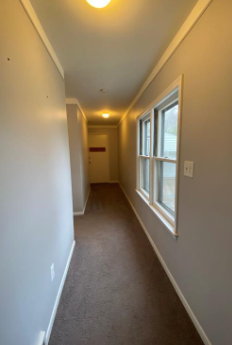a hallway with a window and a carpeted floor