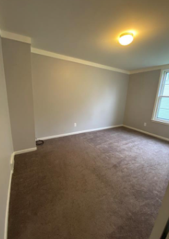 an empty living room with a carpeted floor and a window