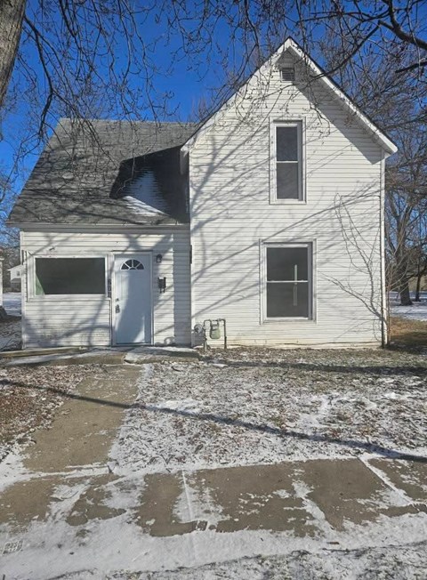 A white house with a grey roof and a small porch.