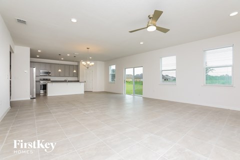 an empty living room and kitchen with a ceiling fan