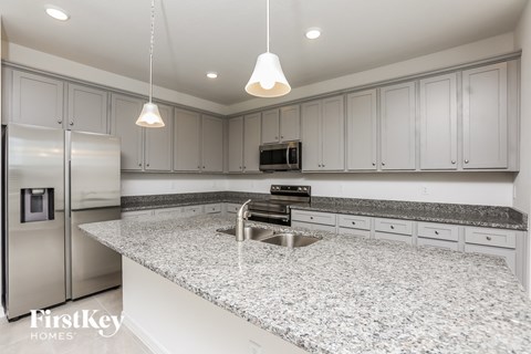 a white kitchen with granite counter tops and white cabinets