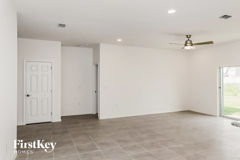 an empty living room with white walls and a ceiling fan
