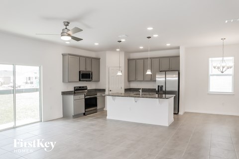 a white kitchen with stainless steel appliances and a large island