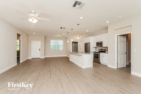 an open kitchen and living room with white cabinets and wood flooring