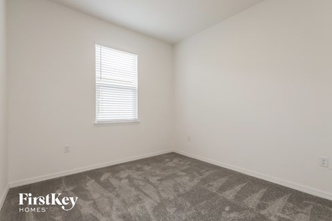 a bedroom with white walls and carpet and a window