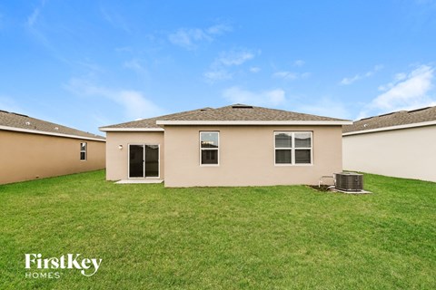 a beige house with a grassy yard and a blue sky