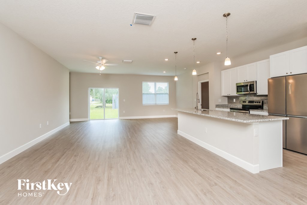 A spacious kitchen and living room with wooden floors and white walls.