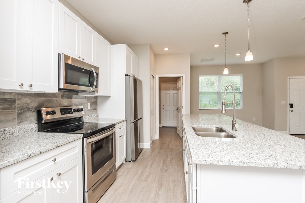 A kitchen with white cabinets and a granite countertop.