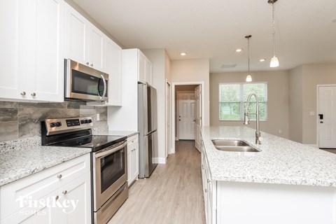 A kitchen with white cabinets and a granite countertop.