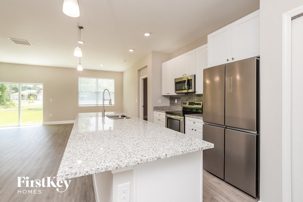 A kitchen with a granite countertop and stainless steel appliances.
