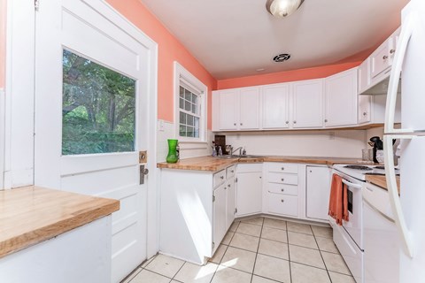 A kitchen with white cabinets and a wooden counter top.