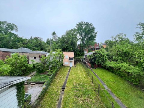 A view of a green yard with a fence and a building in the background.