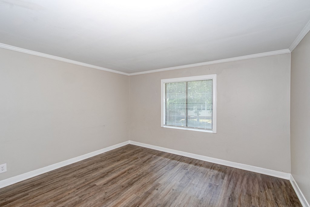 an empty room with wooden floors and a window