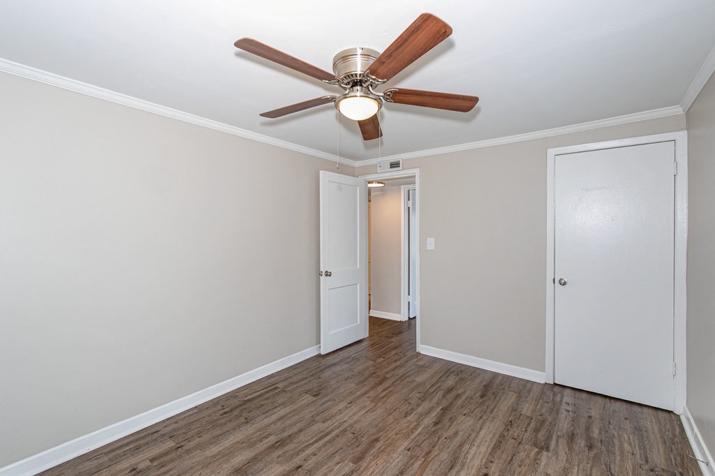 an empty room with a ceiling fan and a door to a hallway