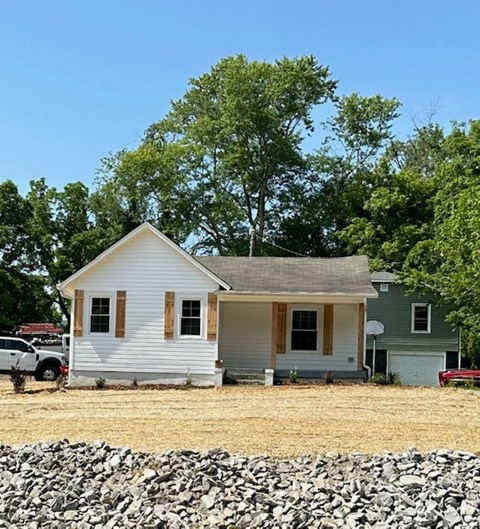 a small white house with a gravel driveway