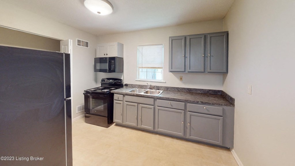 A kitchen with a black refrigerator, black stove, and black oven.