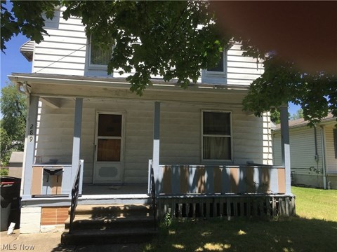 a white house with a porch and a fence