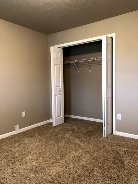 an empty bedroom with a closet with a white door