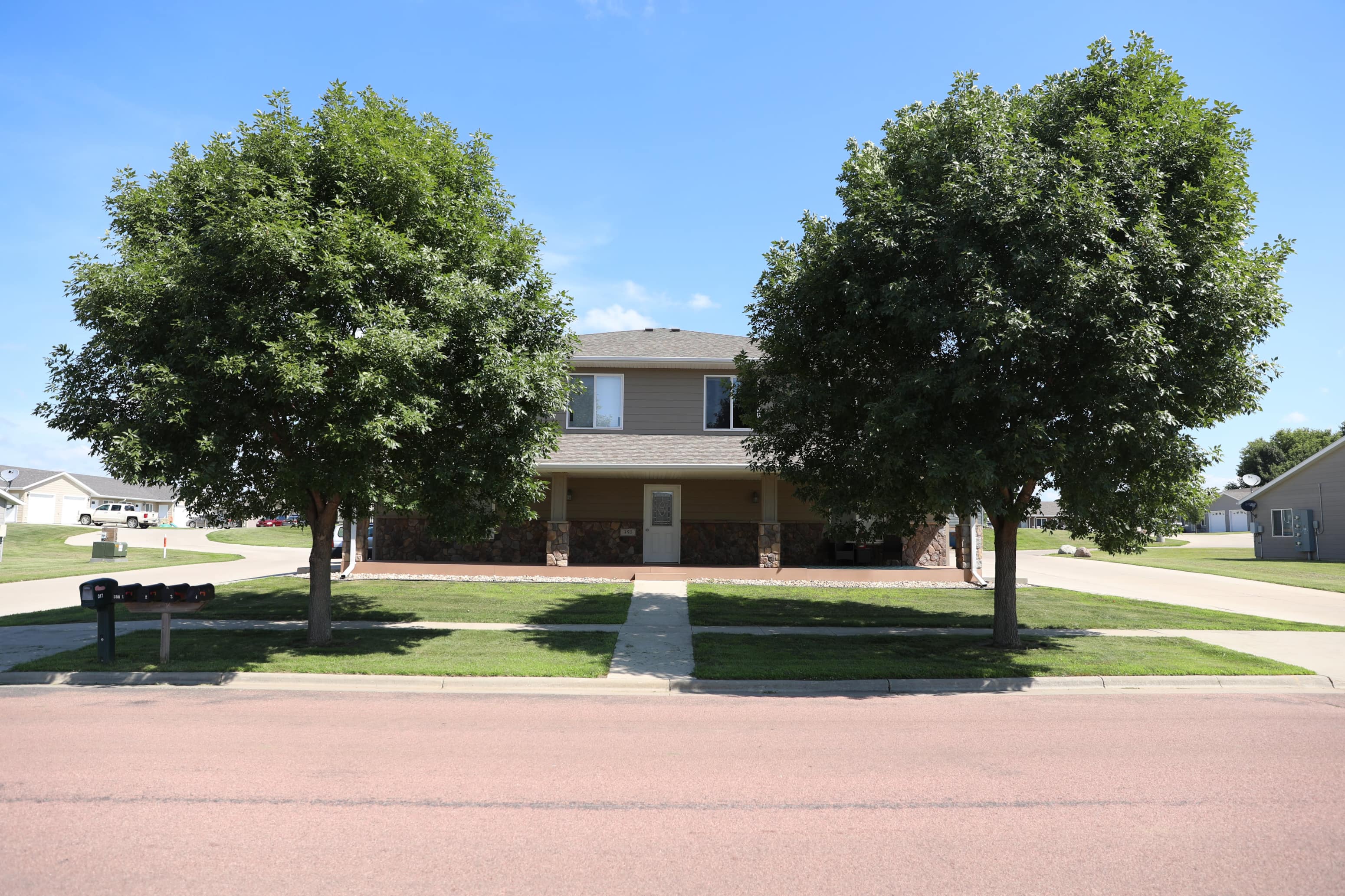 A building is surrounded by two trees and a grassy area.