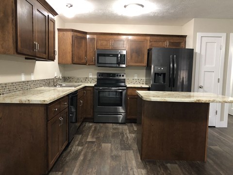 A kitchen with dark wood cabinets and black appliances.