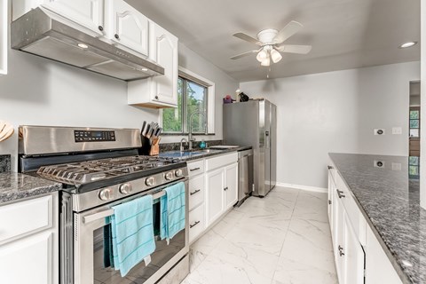 A modern kitchen with a stainless steel oven and white cabinets.